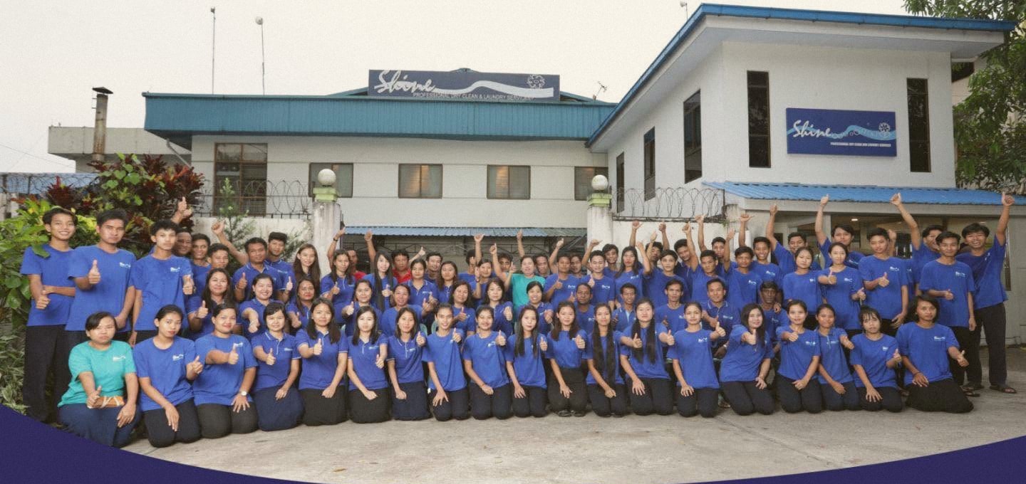 Shine professional laundry original team gathering in front of the building