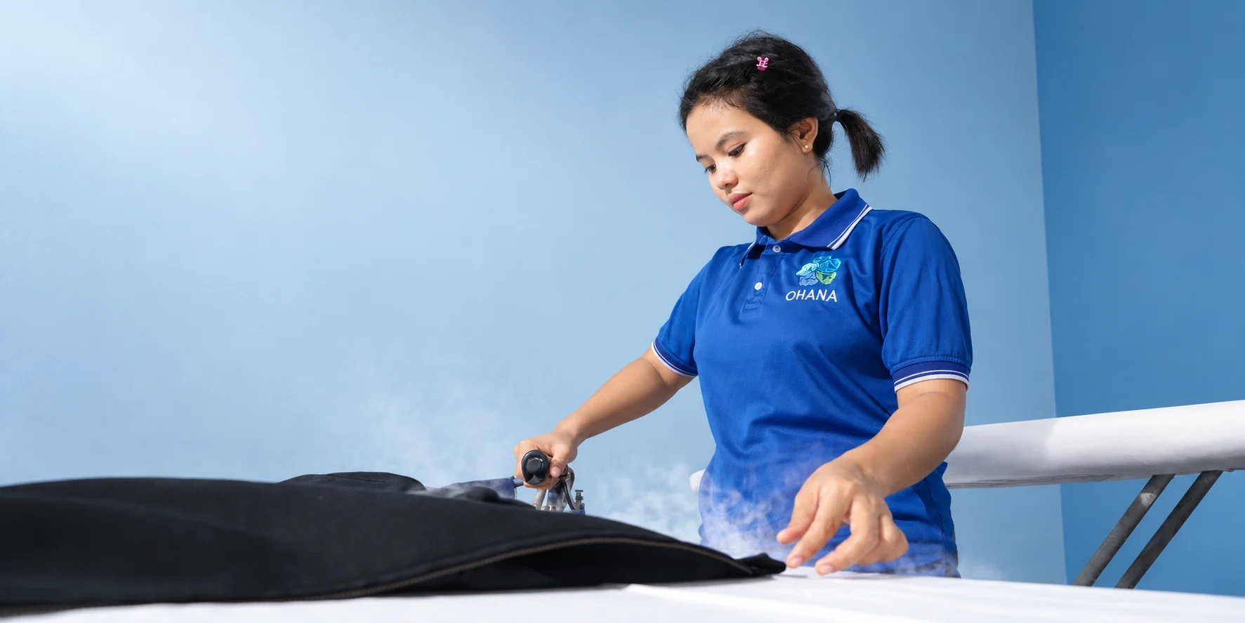 Ohana team member carefully steam pressing a black garment